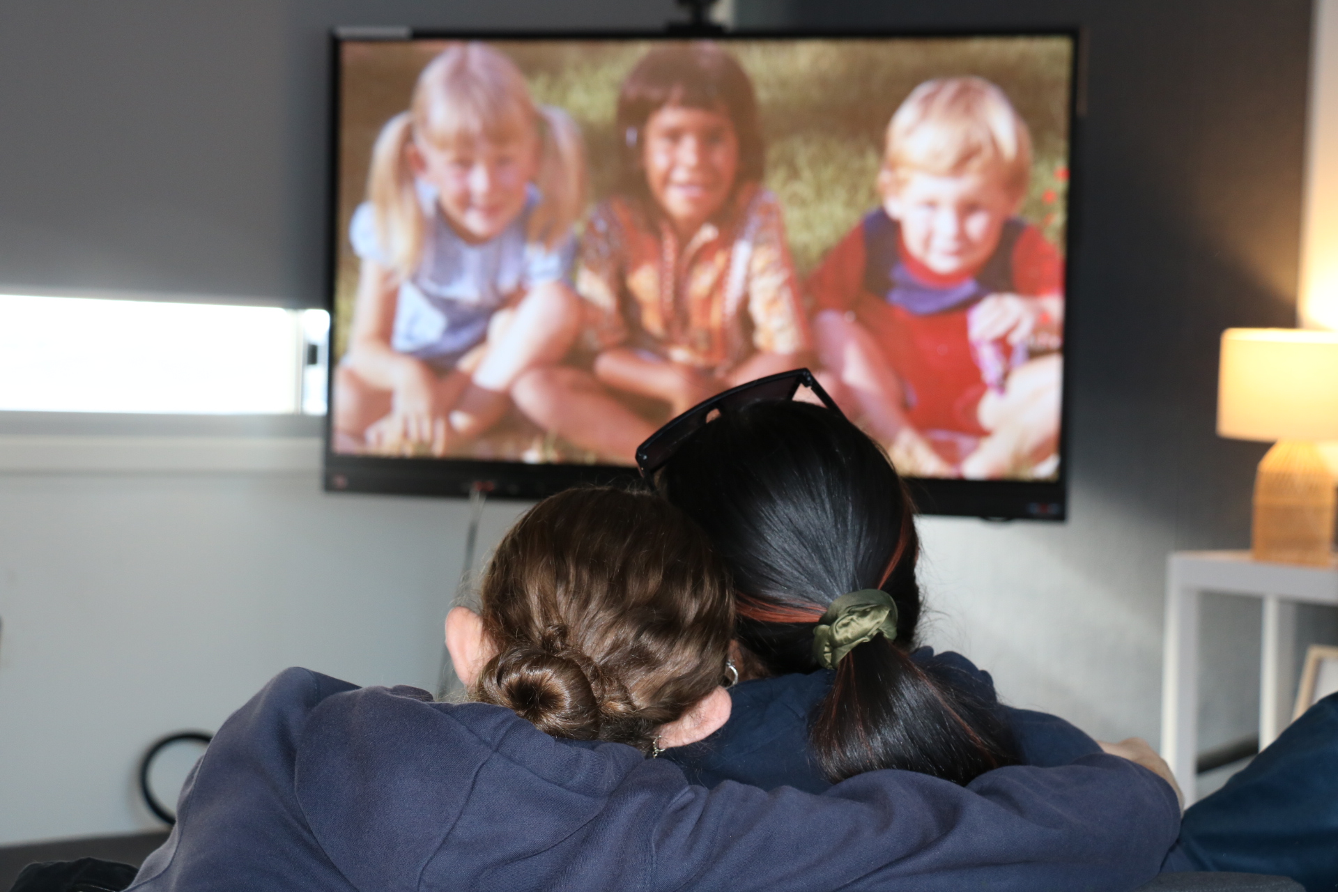 Two students sitting with their heads together watching a documentary