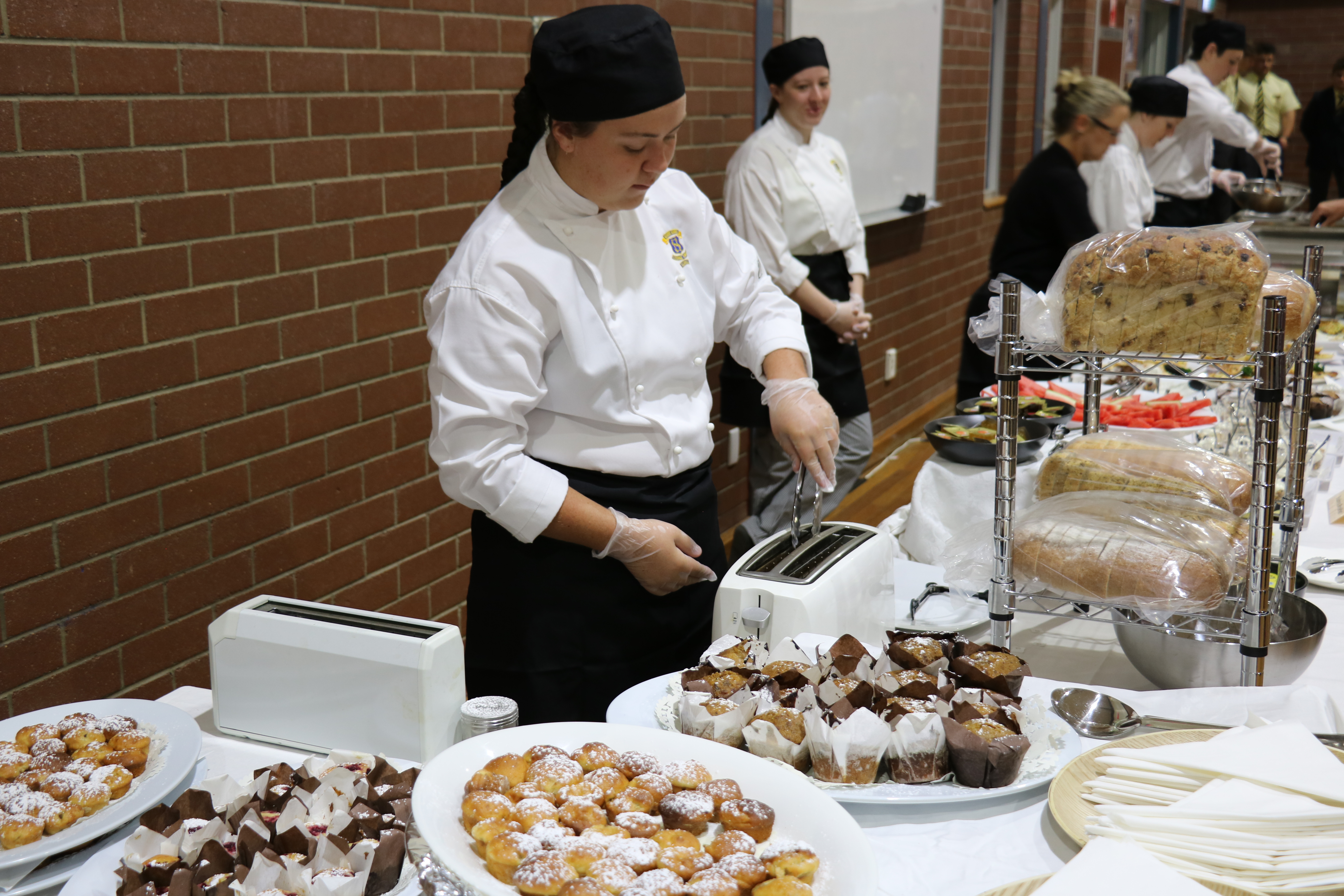 A hospitality student serving food at an event.